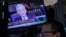 FILE - A screen shows Federal Reserve Chair Jerome Powell speaking as a trader works inside a post on the floor of the New York Stock Exchange in New York City, August 27, 2021. 