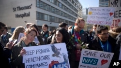 Sejumlah dokter junior di Inggris membawa poster berisi permintaan mereka kepada pemerintah dalam aksi mogok kerja selama 48-jam di luar Rumah Sakit St Thomas di London, pada 26 April 2016. (Foto: AP/Matt Dunham)