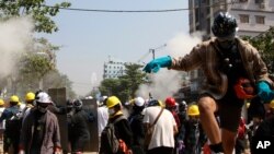 Protesters are dispersed as riot police fired tear gas behind a makeshift barricade in Yangon, Myanmar, March 7, 2021.