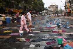 Personas caminan en una calle llena de bolsas de agua para usar contra los gases lacrimógenos, durante una protesta contra el golpe militar.en el cruce de Hledan, en Rangún, Myanmar, el 14 de marzo de 2021.