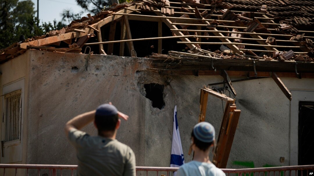 Dos personas observan los daños causados por un proyectil disparado desde Líbano, en un inmueble cerca de Safed, en el norte de Israel, el 25 de septiembre de 2024.