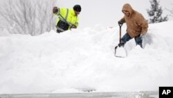 Mark Settlemyer, left, gets help clearing snow from the roof of his mother's house from Ken Wesley in Lancaster, N.Y., Nov. 19, 2014.