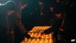 FILE - People light candles by the monument at the Birkenau Nazi death camp in Oswiecim, Poland, January 27, 2024. Survivors of Nazi death camps marked the 79th anniversary of the liberation of the Auschwitz-Birkenau camp during World War II in a ceremony in southern Poland.