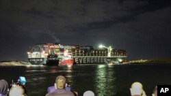 The cargo ship Ever Given, wedged across the Suez Canal and blocking traffic in the vital waterway, is seen March 27, 2021. Tugboats and a specialized suction dredger worked to dislodge the ship, which has been stuck since Tuesday.