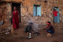 Tigrayans who fled the conflict in Ethiopia's Tigray region, start wood fires to prepare dinner, in front of their temporary shelters at Umm Rakouba refugee camp in Qadarif, eastern Sudan, Dec. 7, 2020.