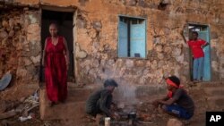 Tigrayans who fled the conflict in Ethiopia's Tigray region, start wood fires to prepare dinner, in front of their temporary shelters at Umm Rakouba refugee camp in Qadarif, eastern Sudan, Dec. 7, 2020. 