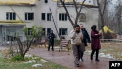 FILE - People walk next to a damaged hospital building as a result of a Russian drone attack in Kyiv, on November 29, 2024, amid the Russian invasion of Ukraine. With snow on the ground, NATO chief Mark Rutte said Russia is using the onset of winter as a weapon in the war.