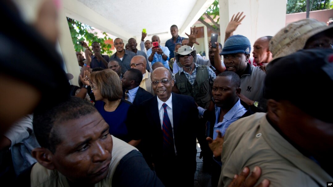 Former Haitian President Jean-Bertrand Aristide, center, smiles as he greets supporters outside the courthouse in Port-au-Prince, Haiti, March 20, 2017. 