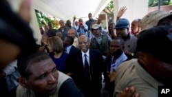 Former Haitian President Jean-Bertrand Aristide, center, smiles as he greets supporters outside the courthouse in Port-au-Prince, Haiti, March 20, 2017. 