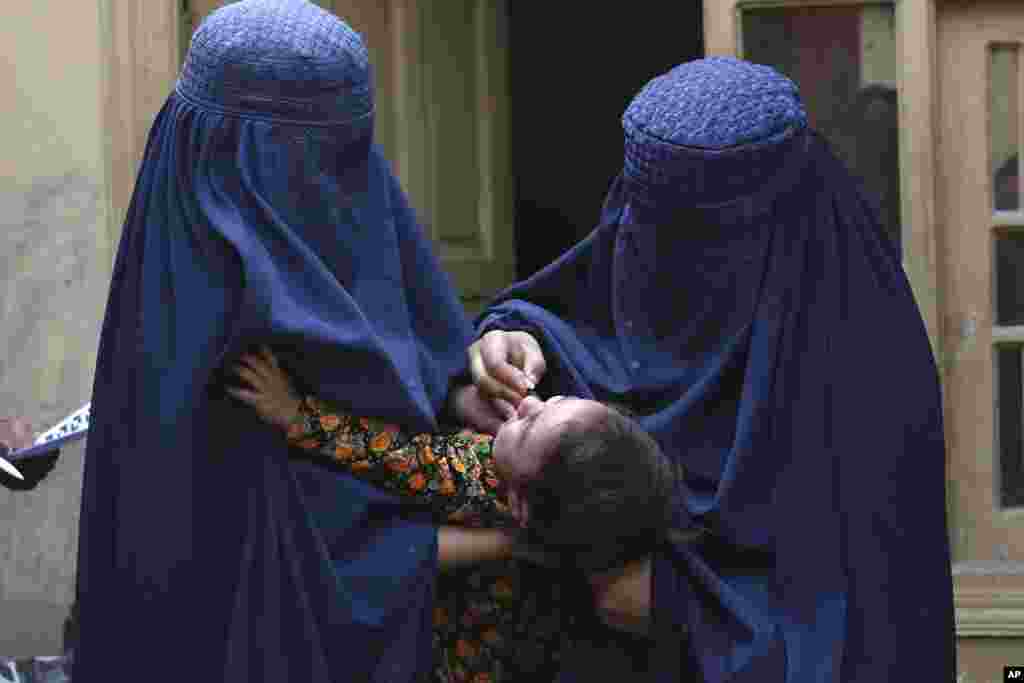 A health worker, right, administers a polio vaccine to a child in a neighborhood of Jalalabad, east of Kabul, Afghanistan.