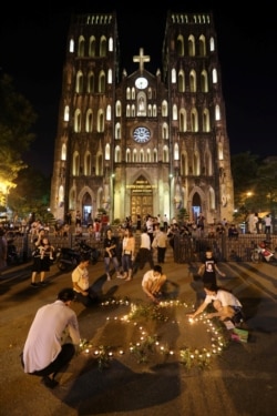 Vietnamese residents light candles during a prayer for 39 people found dead in the back of a truck near London, in front of Hanoi Cathedral in Hanoi, Oct. 27, 2019.