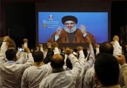 FILE - Hezbollah scouts raise their fists and cheer as they listen to a speech of Hezbollah leader Hassan Nasrallah, via video link, during a rally in southern Beirut, Lebanon, April 22, 2019.