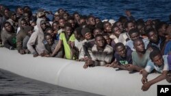 FILE - Migrants wait to board the MV Aquarius, as 193 people and two corpses are recovered, Jan. 13, 2017, from international waters in the Mediterranean Sea about 22 miles (35 km) north of Sabrata, Libya. 