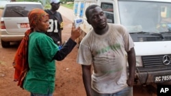 A health worker (L) uses a thermometer to screen a man at a makeshift road block run by Guinean security forces outside the town of Forecariah, Guinea, Sept. 7, 2014.