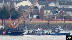 Sebuah kapal Penjaga Pantai dengan derek terlihat sedang beroperasi di dekat reruntuhan helikopter Black Hawk di Sungai Potomac, yang terlihat dari Bandara Nasional Ronald Reagan Washington, pada Jumat, 31 Januari 2025, di Arlington, Virginia. (Alex Brandon/AP)