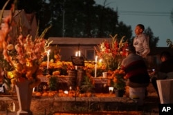 Families gather by the tomb of their dearly departed, as they celebrate the Day of the Dead, at the San Gregorio Atlapulco cemetery on the outskirts of Mexico City, Nov. 1, 2024.