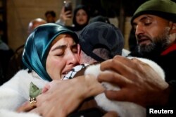 People embrace as Palestinian prisoners arrive on a bus after they were released from an Israeli jail as part of a hostages-prisoners swap and a ceasefire deal in Gaza between Hamas and Israel, in Ramallah, in the Israeli-occupied West Bank, Feb. 27, 2025.