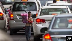 A young boy sells flowers to commuters at a busy cross road in New Delhi, India on June 1, 2016.