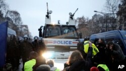 프랑스 노란조끼 시위대가 15일 경찰 물대포 앞에서 연좌시위를 벌이고 있다.