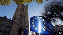 FILE - The sun shines through European Union flags tied to railings outside parliament in London, Jan. 22, 2019. 