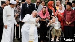 Pope Francis gestures next to the Grand Imam of Istiqlal Mosque Nasaruddin Umar during a family photo following an interreligious meeting with religious leaders at the Istiqlal Mosque in Jakarta, Indonesia on Sept. 5, 2024.