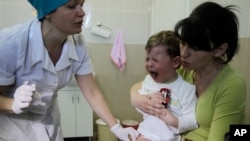 FILE - A boy reacts after receiving a vaccine from a nurse at Children's Hospital No. 1 in Kyiv, Ukraine.