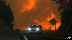 ARCHIVO – Un incendio arde sobre la autopista 330 mientras un vehículo de emergencia circula el sábado 7 de septiembre de 2024, cerca de Running Springs, California.