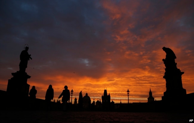 FILE - People cross the medieval Charles Bridge as the sun rises in Prague, Czech Republic, Thursday, Oct. 17, 2013. (AP Photo/Petr David Josek)