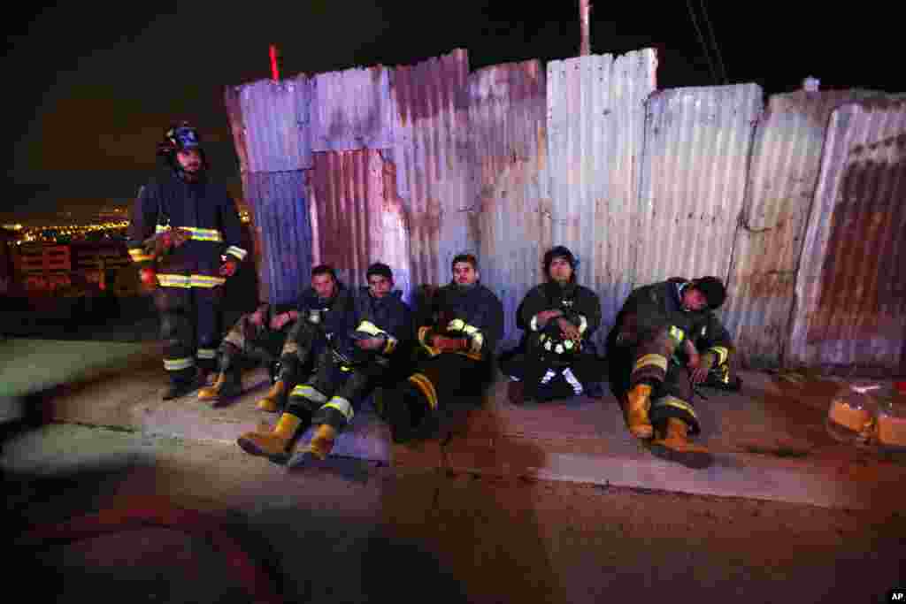 Bombeiros fazem um pequeno intervalo de descanso após horas a combater o fogo que alcançou áreas urbanas em Valparaiso, Chile, Abril 14, 2014.