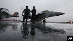 U.S. Navy deck crew members stand in front of an F/A-18 fighter jet on the aircraft carrier USS George Washington in Hong Kong, November 9, 2011. 