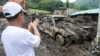 A villager takes a photo of a damaged car after a recent landslide triggered by Tropical Storm Trami struck Talisay, Batangas province, Philippines leaving thousands homeless and several villagers dead on Saturday, Oct. 26, 2024.