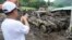 A villager takes a photo of a damaged car after a recent landslide triggered by Tropical Storm Trami struck Talisay, Batangas province, Philippines leaving thousands homeless and several villagers dead on Saturday, Oct. 26, 2024.
