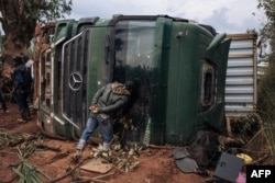 FILE - A passer-by looks inside an overturned truck in the middle of National Road 27 in Ituri Province, northeastern Democratic Republic of Congo, Sept. 16, 2020.