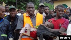 Rescuers carry a child who survived after a mudslide at a rubbish landfill in the Dar Es Salam neighbourhood, on the outskirts of the capital Conakry, Guinea, Aug. 22, 2017. 