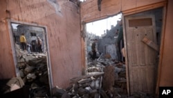 ခန်ယူနစ်စ်မြို့မှာ အစ္စရေးဗုံးကြဲတိုက်ခိုက်ခံရပြီးနော် ပျက်စီးသွားတဲ့အဆောက်အဦးတွေကြားမှာ လည့်လည်ကြည့်ရှုနေတဲ့ ပါလက်စတိုင်းများ။ ​(ဒီဇင်ဘာ ၁၊ ၂၀၂၃)