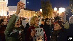 FILE - People hold candles aloft as they protest against judicial reforms proposed by the president and ruling party Law and Justice, in Warsaw, Poland, Oct. 1, 2017.