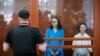 La directora de teatro Zhenya Berkovich, a la derecha, y la dramaturga Svetlana Petriychuk miran a los medios mientras están parados en una jaula de vidrio antes de una audiencia en un tribunal en Moscú, Rusia, el lunes 8 de julio de 2024. AP