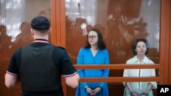 La directora de teatro Zhenya Berkovich, a la derecha, y la dramaturga Svetlana Petriychuk miran a los medios mientras están parados en una jaula de vidrio antes de una audiencia en un tribunal en Moscú, Rusia, el lunes 8 de julio de 2024. AP