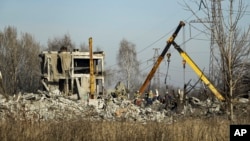 Workers clean rubbles after a Ukrainian rocket strike in Makiivka, in Russian-controlled Donetsk region, eastern Ukraine, Tuesday, Jan. 3, 2023.