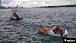 A Canadian Coast Guard ship tows floatation devices used by Americans to the Canadian side of the St. Clair River between Michigan and Ontario, Aug. 21, 2016.