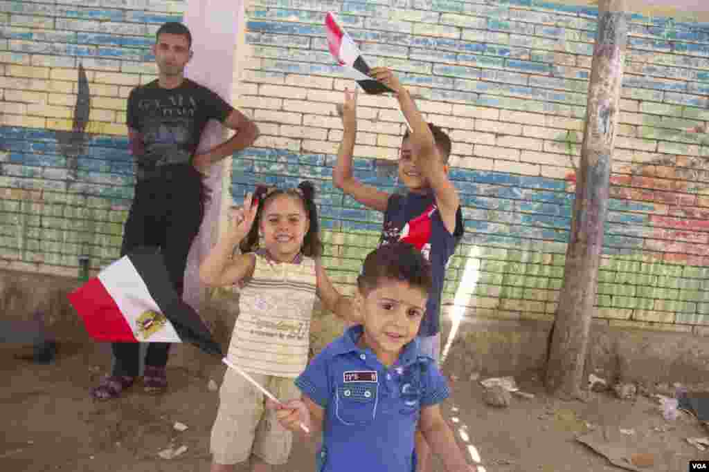 Children wave flags outside a polling station in Cairo, May 27, 2014. (Hamada Elrasam /VOA)