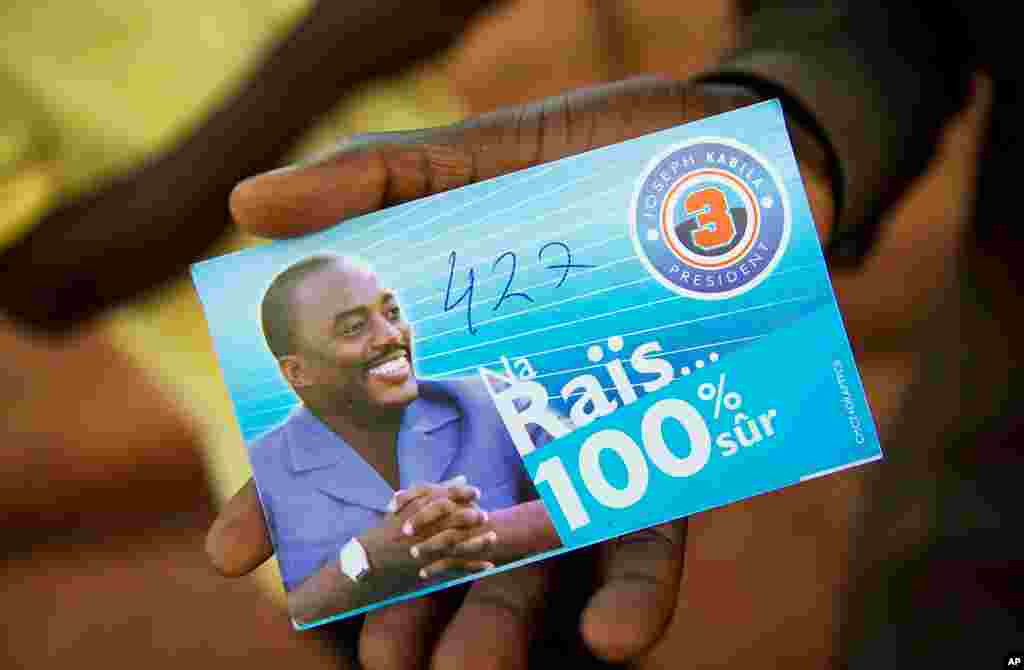 A supporter of incumbent president Joseph Kabila shows a card of the candidate, marked also with the number of this supporter's candidate for the legislatives in Lubumbashi, November 26, 2011. (AFP)