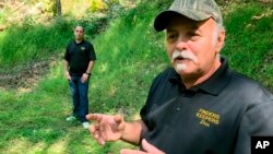 In this Sept. 20, 2018 photo, Dennis Parada, right, and his son Kem Parada stand at the site of the FBI's dig for Civil War-era gold in Dents Run, Pennsylvania. (AP Photo/Michael Rubinkam)