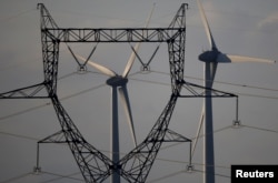 A high-tension electricity power line pylon is seen in front of power-generating windmill turbines at a wind park in Couffe near Nantes, France, on January 27, 2023. (REUTERS/Stephane Mahe)