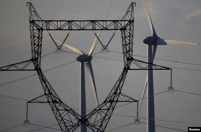 A high-tension electricity power line pylon is seen in front of power-generating windmill turbines at a wind park in Couffe near Nantes, France, on January 27, 2023. (REUTERS/Stephane Mahe)