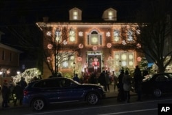 File - Pengunjung berjalan di sepanjang trotoar di Dyker Heights, Brooklyn, untuk melihat pernak-pernik Natal tahunan yang mewah di lingkungan tersebut, 20 Desember 2022. (Ted Shaffrey/AP)