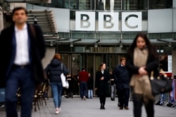FILE - Pedestrians walk under BBC signage at Broadcasting House in London, Britain, Jan. 29, 2020.