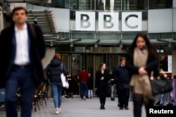 FILE - Pedestrians walk past a BBC logo at Broadcasting House in London, Britain, Jan. 29, 2020.