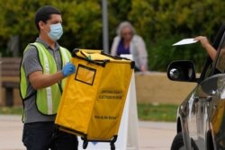 FILE - Voters drop off ballots in a special election for California's 25th Congressional District during the coronavirus outbreak, May 12, 2020, in Simi Valley, California.