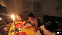 Anak-anak belajar di malam hari, diterangi lilin akibat pemadaman listrik di sebuah hunian di ibu kota Libya, Tripoli, 26 Agustus 2021.
